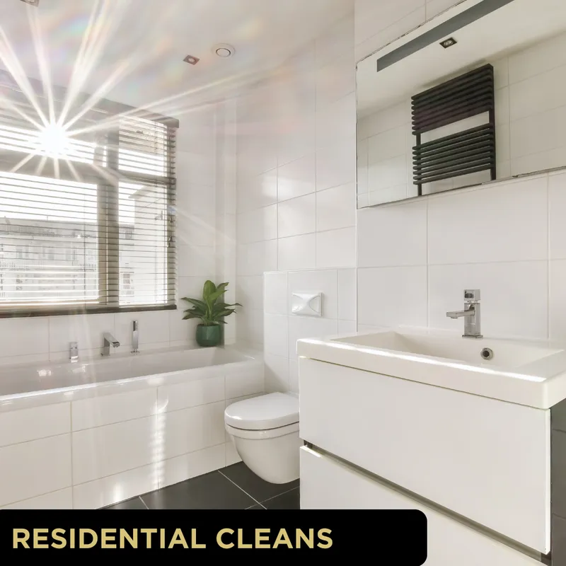 Sunlit modern tiled bathroom with spotless bathtub, toilet, sink and plant illustrating Glo Clean residential cleans in York